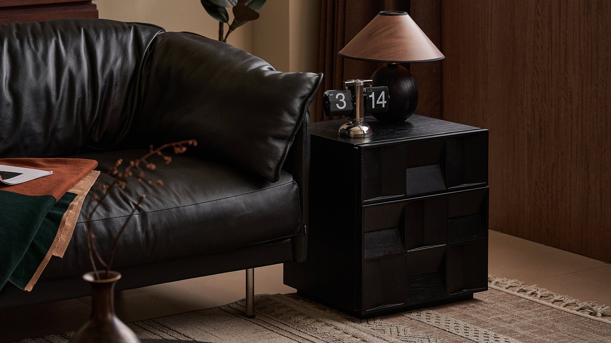 Black leather sofa and nightstand with decorative items in a room setting