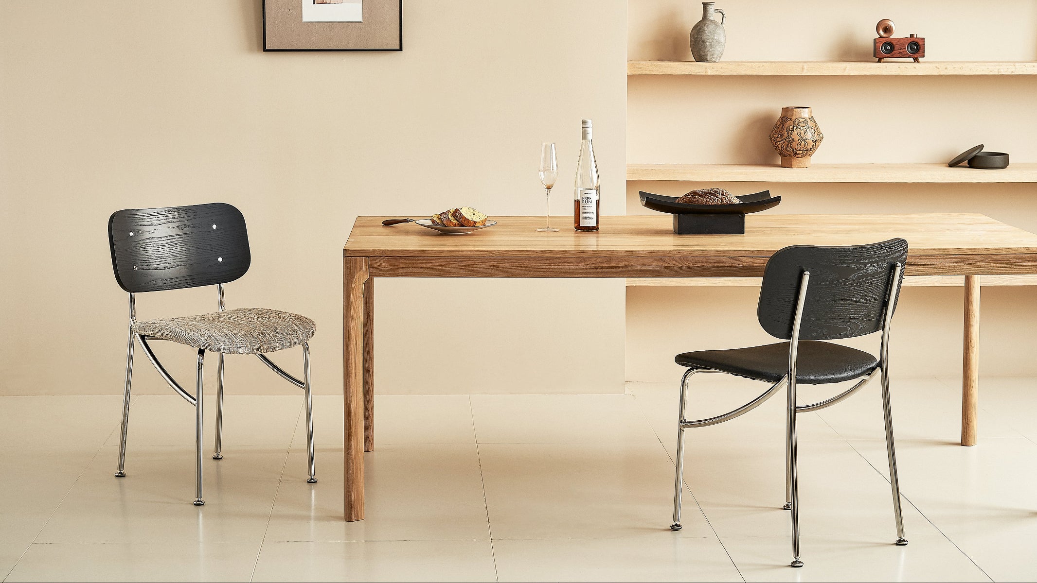 Dining table with two chairs in a room with a shelf and decor items.