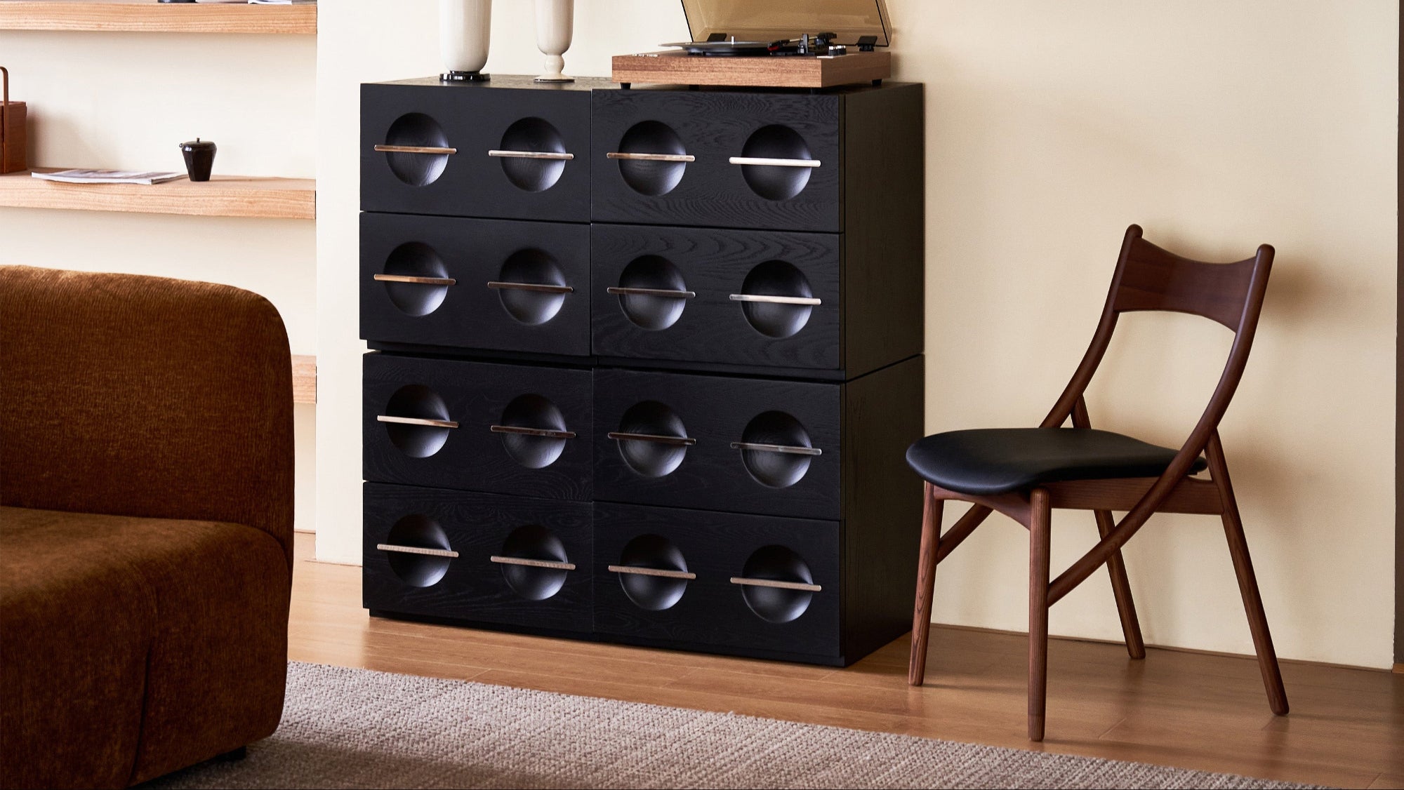Black storage cabinet with round handles in a room with a chair and sofa.