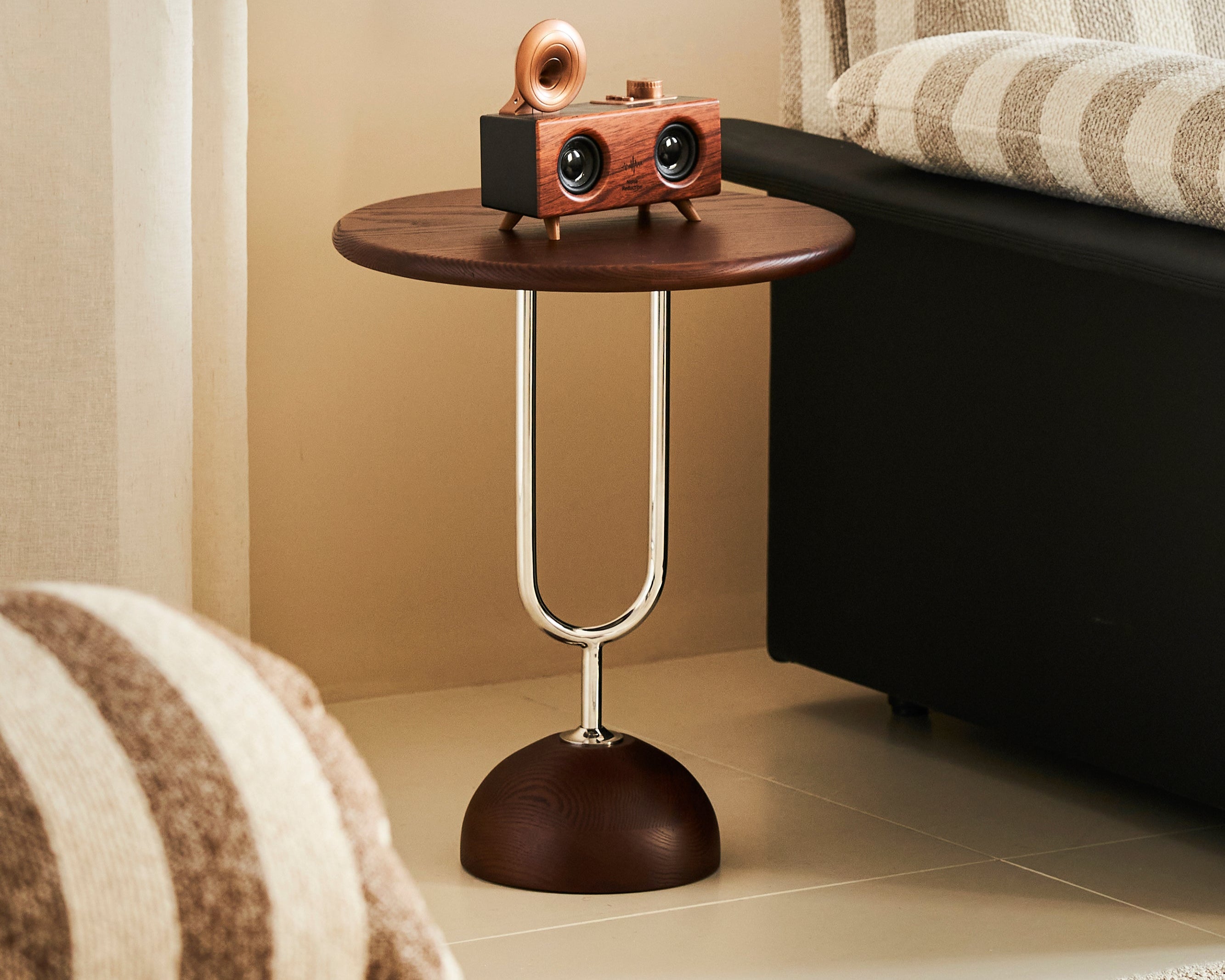 Small wooden side table with a decorative object next to a striped armchair in a room.