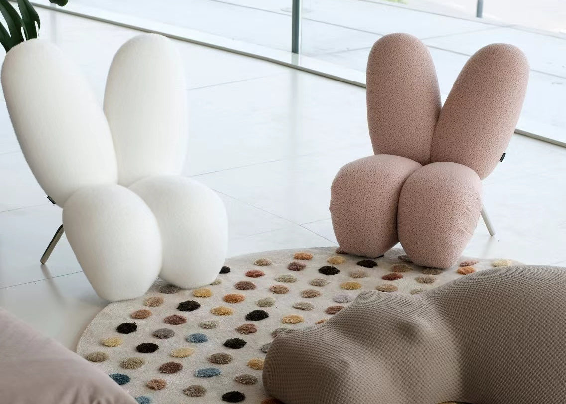 Modern interior with a unique pink bunny-shaped chair on a colorful rug.