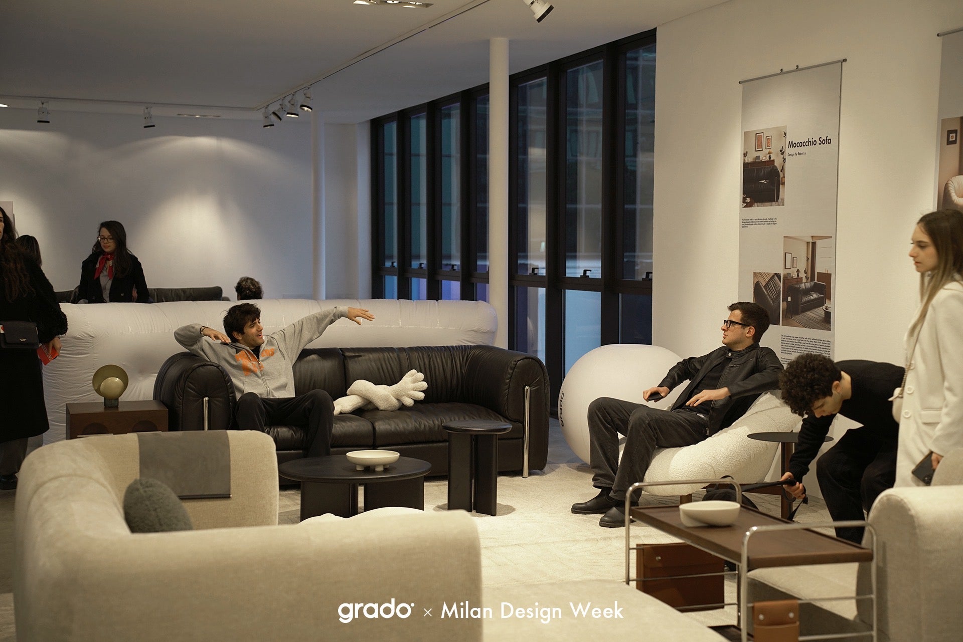 Modern living room with people interacting, featuring Grado and Milan Design Week branding.