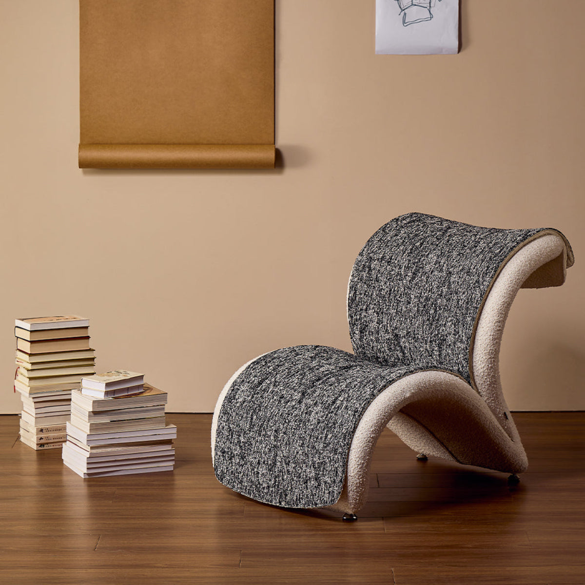 Modern chair against a beige wall with a stack of books and a drawing.