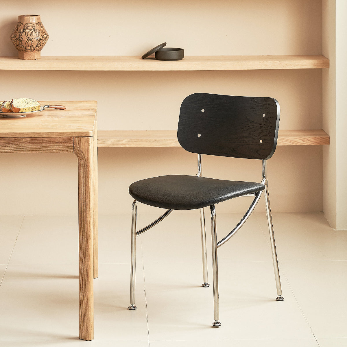 Black chair with metal legs in front of a wooden table.