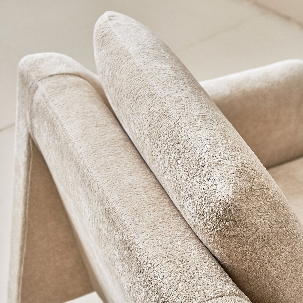 Close-up of a beige upholstered chair with a soft texture.