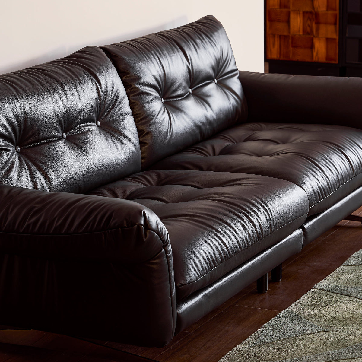 Brown leather sofa in a room with a wooden floor and a window.