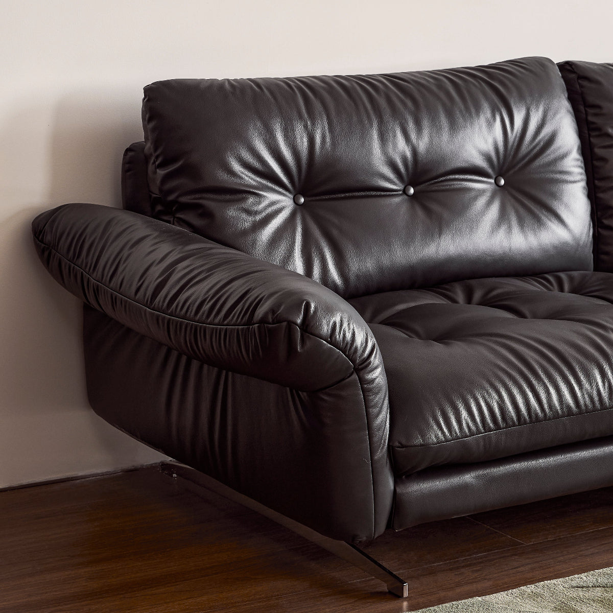 Black leather sofa in a room with wooden floor and light-colored walls