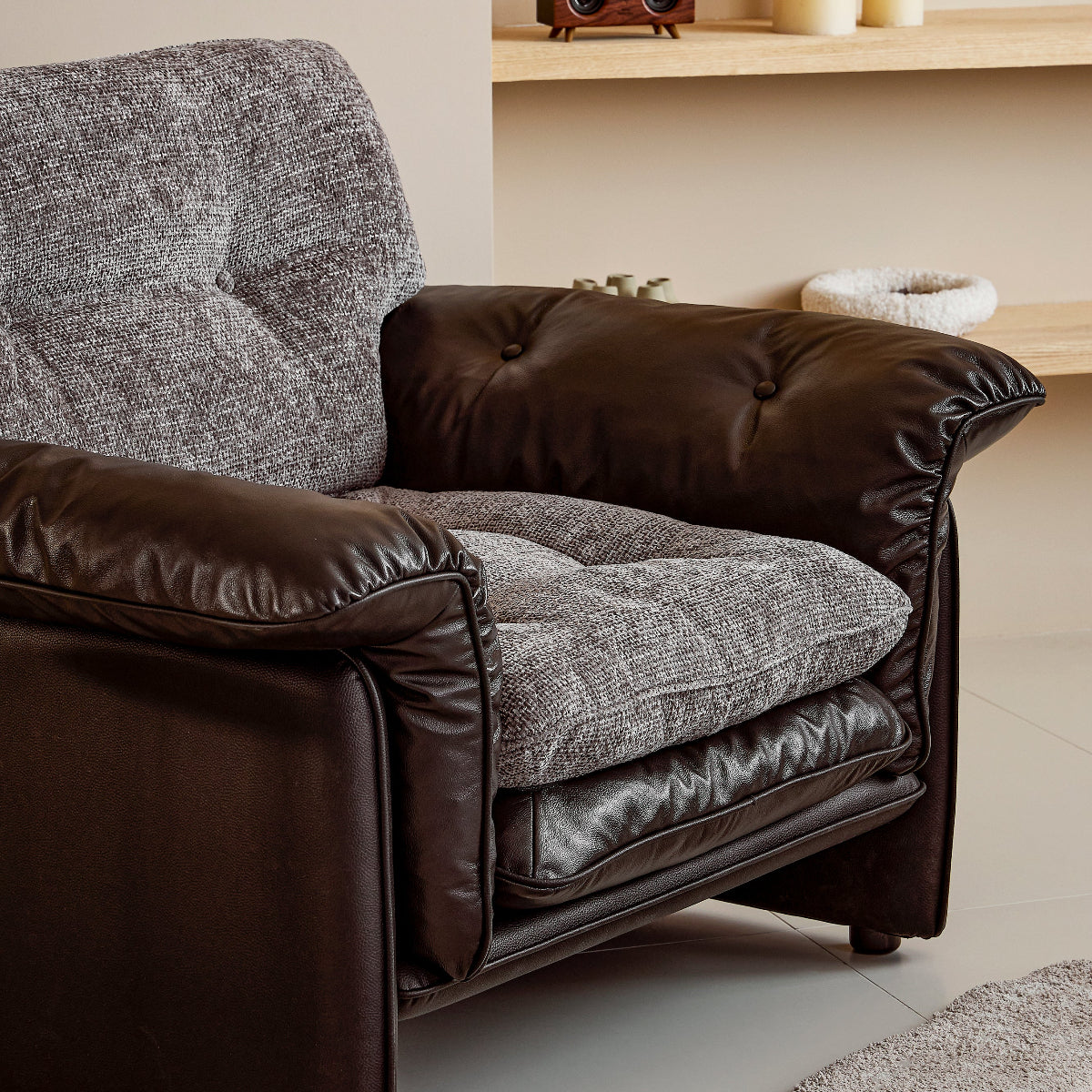 Brown armchair with textured cushions in a room with a shelf and candles.