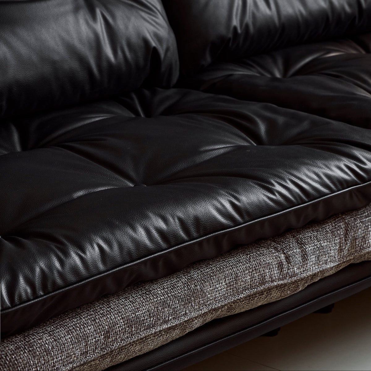 Brown leather sofa with a textured blanket on a light-colored floor.