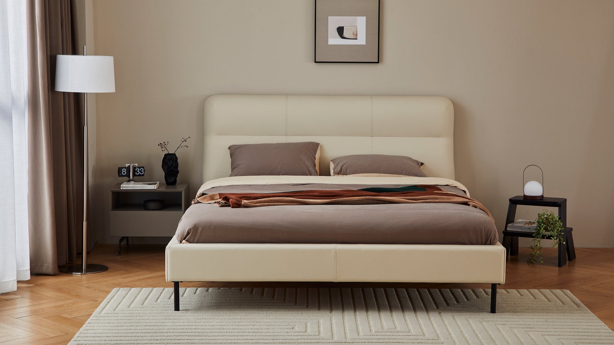 Beige bed in a room with a lamp, nightstands, and decor.